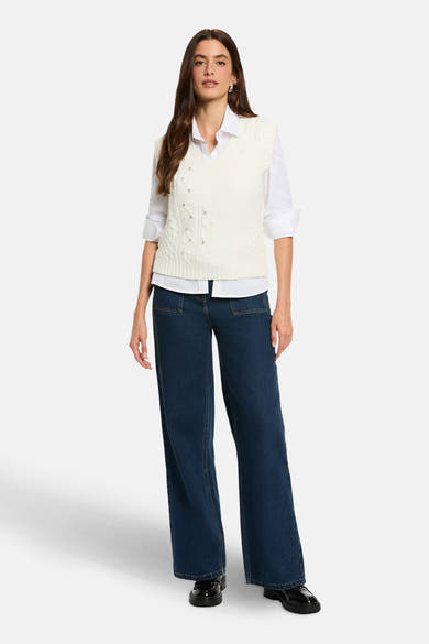 Witte mouwloze top van Morgan de Toi, gedragen over een wit overhemd met lange mouwen en een donkerblauwe wijde jeans.