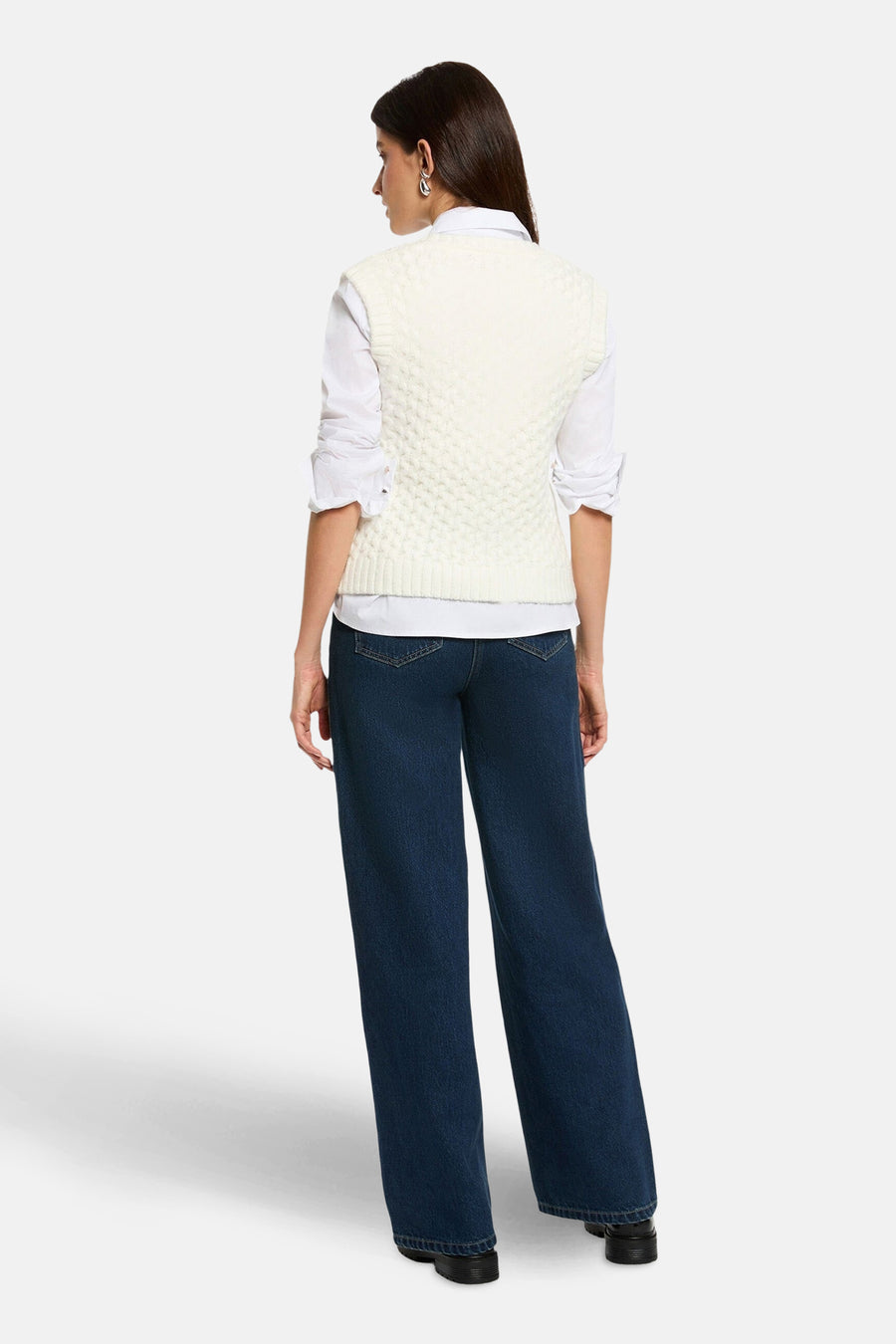 Débardeur blanc en maille tressée de Morgan de Toi, porté avec une chemise blanche et un jean ample bleu foncé.
