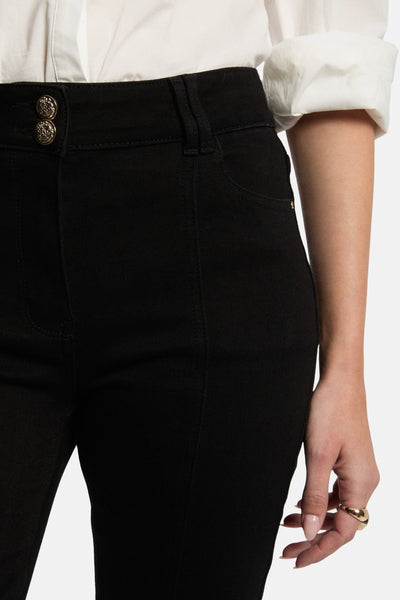 Jean bootcut noir de Morgan de Toi avec deux boutons décoratifs dorés à la taille.