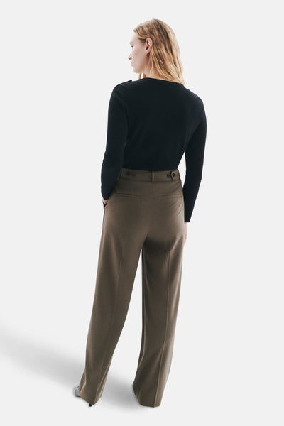 Beige kostuumbroek van CAROLL, hoge taille met twee knopen, gedragen met een zwarte trui.