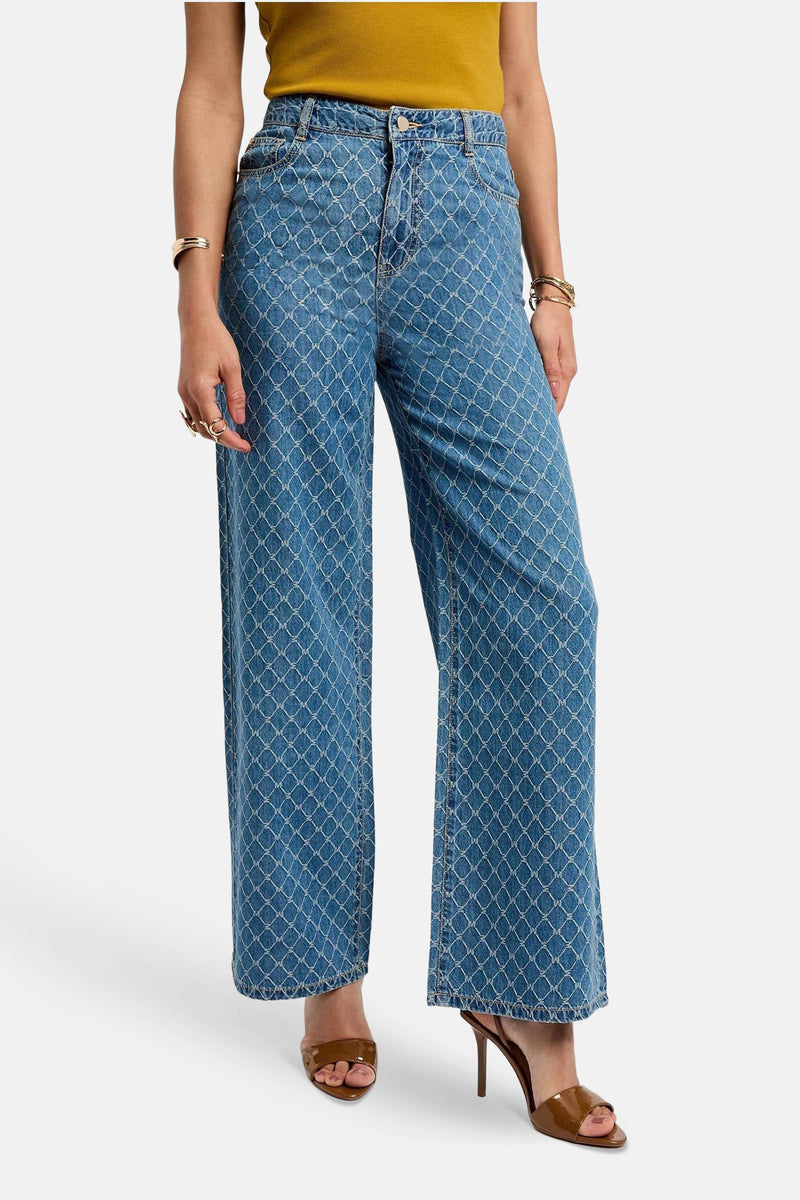 Pantalon en denim bleu moyen de Morgan de Toi, avec motif losange imprimé, porté avec un haut jaune et des mules marron.
