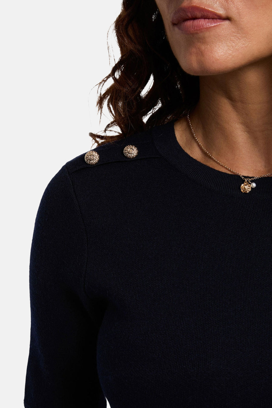 Blauwe jurk met korte mouwen van Morgan de Toi met decoratieve knopen op de schouders en een gouden ketting.