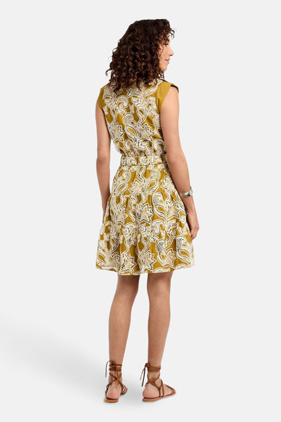 Robe jaune à motifs ajourés de Morgan de Toi, coupe courte et ornée de sandales à brides lacées.
