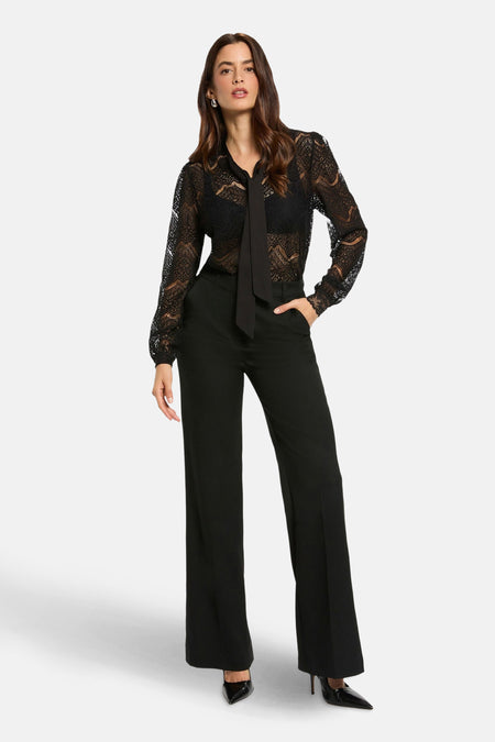 Zwarte blouse met lange mouwen van Morgan de Toi met kantpatroon, gedragen met een zwarte pantalon met hoge taille.