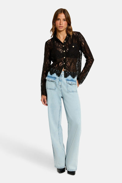 Zwarte blouse met lange mouwen van Morgan de Toi in doorschijnend kant met gouden knopen, gedragen met een high-waisted jeans.
