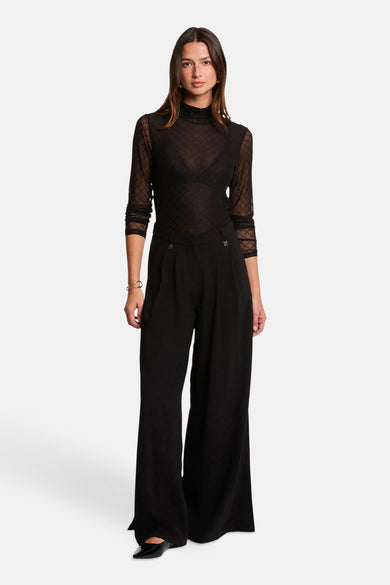Zwarte blouse met lange mouwen van Morgan de Toi met een geometrisch ruitpatroon, gedragen met een zwarte wijde broek.