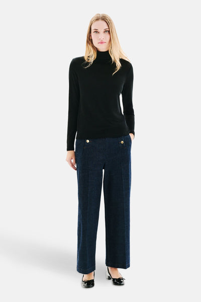 Zwart T-shirt met lange mouwen van CAROLL, gedragen met een marineblauwe broek met gouden knopen en zwarte schoenen.
