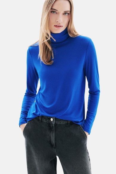 Blauw T-shirt met lange mouwen van CAROLL, gedragen met ronde oorbellen, in close-up.