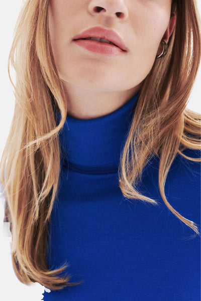 T-shirt bleu à manches longues de CAROLL, porté avec des boucles d'oreilles rondes, en vue rapprochée.