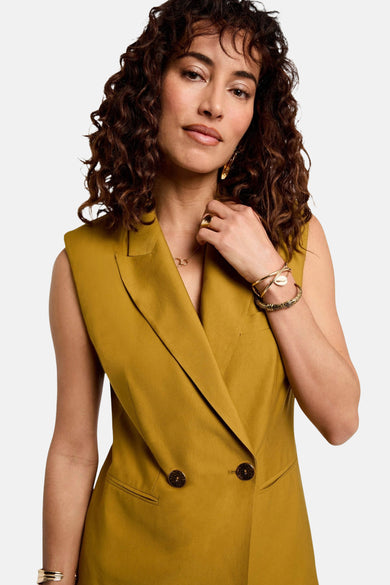 Blazer ocre by Morgan de Toi avec double boutonnage, porté avec des bijoux dorés.

