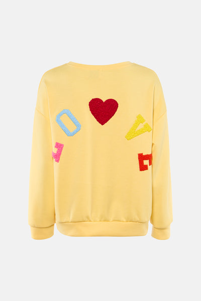 Yellow crewneck sweatshirt with colorful textured appliqué letters and red heart, back view
