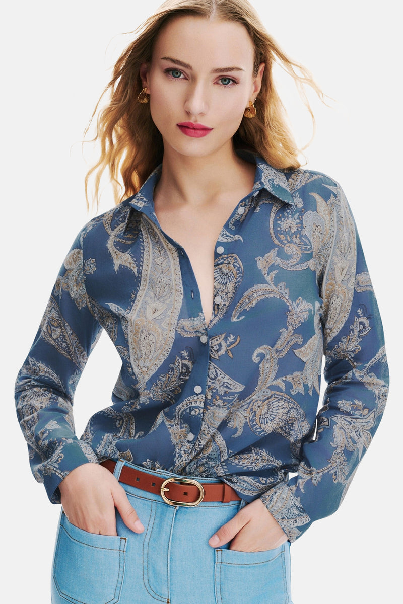 Chemise à manches longues bleue de CAROLL, à motif cachemire, portée avec un jean bleu clair et une ceinture marron.