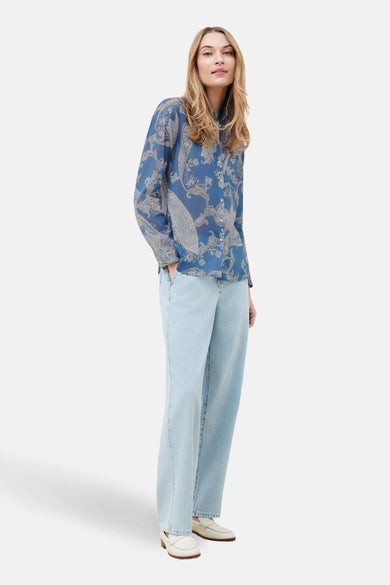 Chemise à manches longues bleue de CAROLL, avec motif cachemire, portée avec un jean délavé et des mocassins blancs.