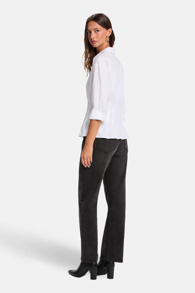 Chemise blanche à manches longues de Morgan de Toi, avec revers roulés, associée à un jean noir.