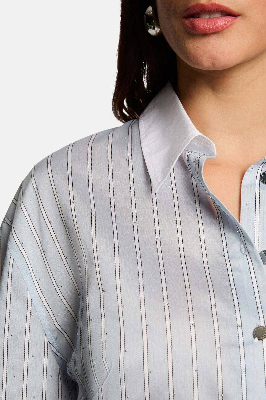Chemise à manches longues bleue à rayures fines de Morgan de Toi, ornée de petits détails scintillants et portée avec des boucles d'oreilles argentées.
