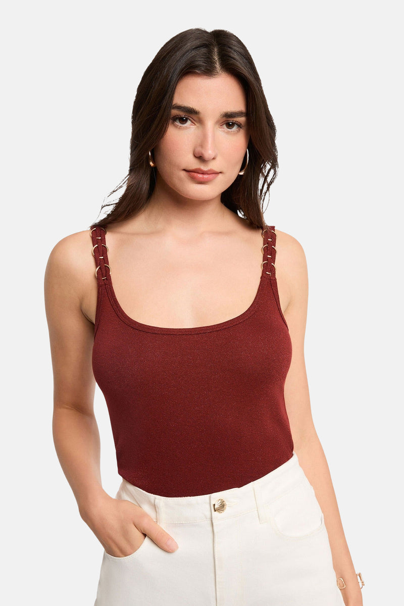 Top de couleur brique de Morgan de Toi à fines bretelles ornées d'anneaux dorés, porté avec un pantalon blanc.
