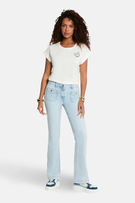 T-shirt blanc à manches courtes de Morgan de Toi, avec motif cœur ornemental, porté avec un jean évasé et des sneakers compensées.
