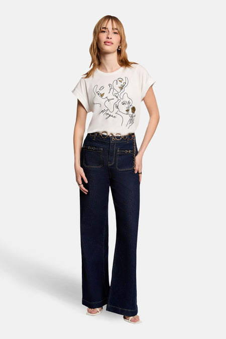 Wit T-shirt met korte mouwen van Morgan de Toi met gezichtenprint, gedragen met een high-waisted jeans en een kettingriem.