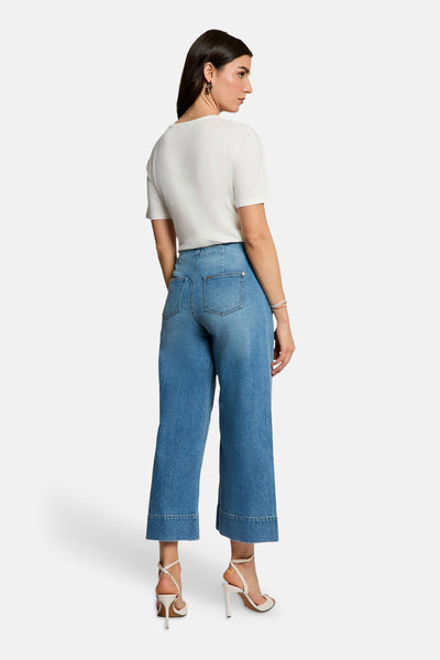 T-shirt blanc de Morgan de Toi, porté avec un pantalon large en denim et des talons aiguilles blancs.