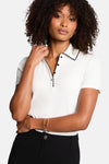 Wit poloshirt met korte mouwen van Morgan de Toi, gedragen met een zwarte broek met hoge taille en enkellaarsjes.
