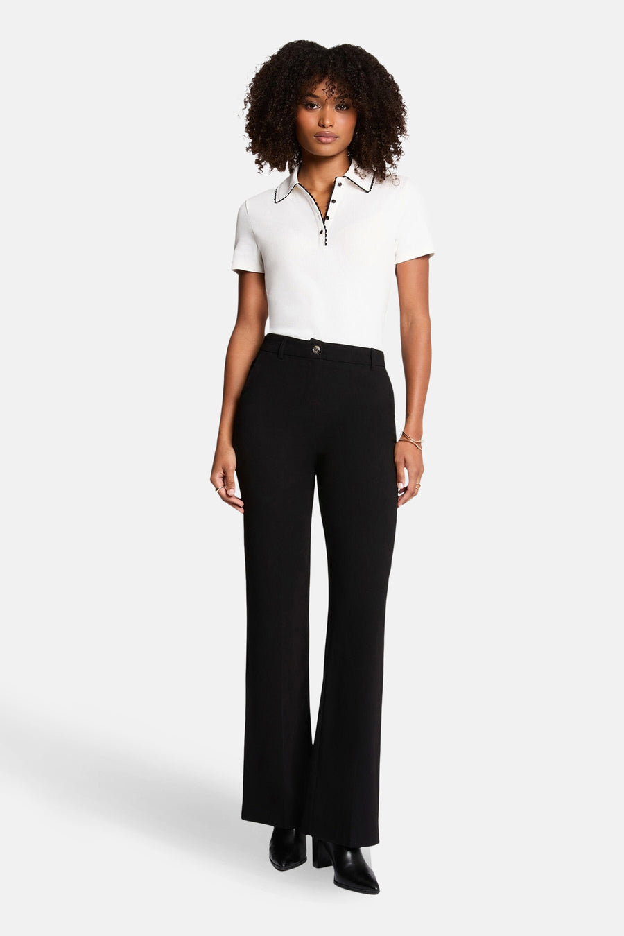 Wit poloshirt met korte mouwen van Morgan de Toi, met zwarte bies rond de kraag, gedragen met een zwarte broek.