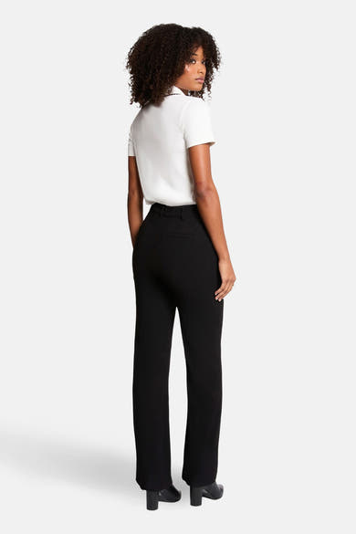 Polo blanc à manches courtes de Morgan de Toi, porté avec un pantalon noir taille haute et des bottines.