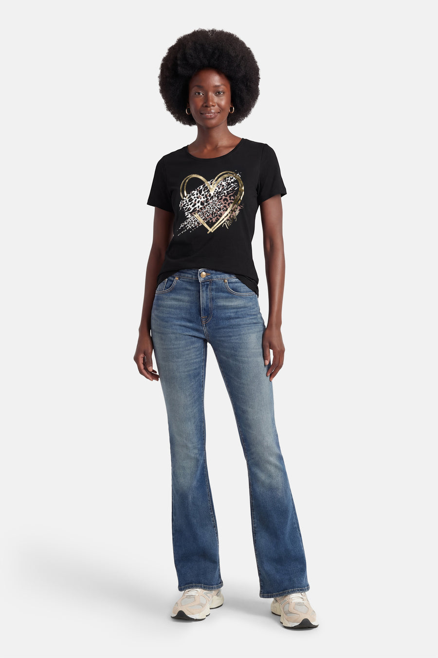 T-shirt noir à manches courtes de Morgan de Toi, avec un imprimé cœur léopard doré, porté avec un jean bleu et des baskets.
