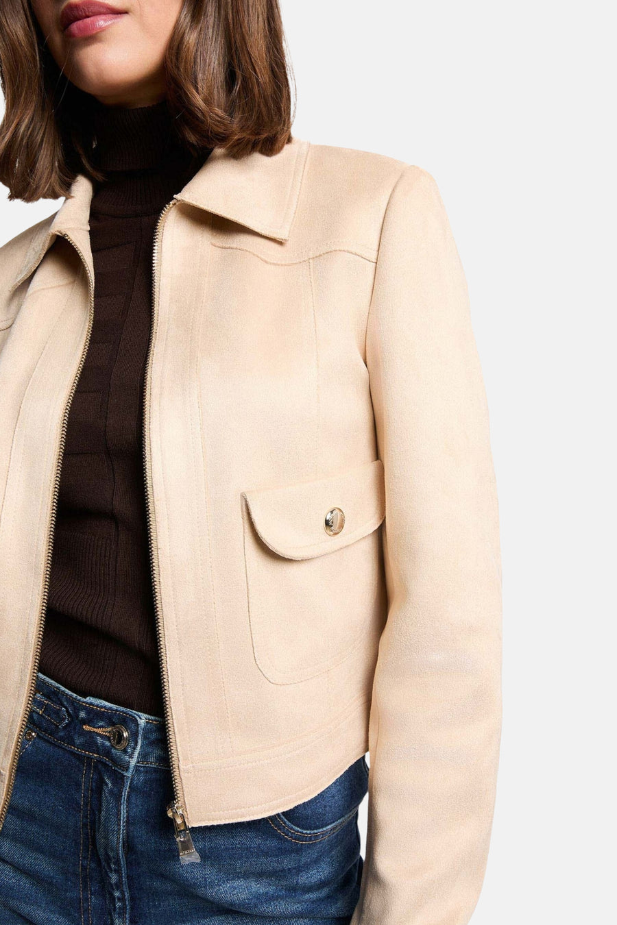 Veste courte beige de Morgan de Toi, avec fermeture éclair et poche à rabat boutonnée, portée sur un pull col roulé marron.