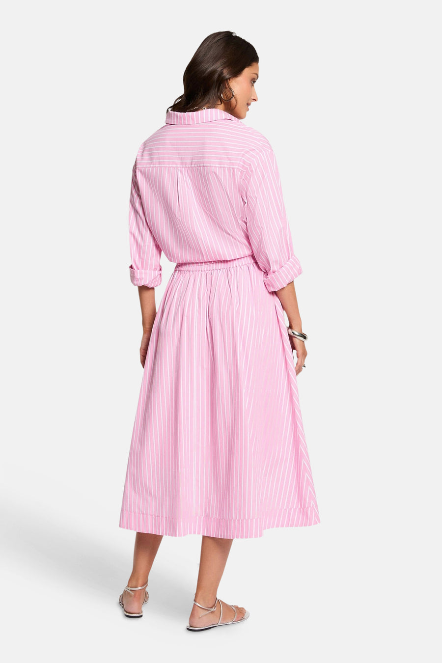 Jupe rose 3/4 à rayures verticales blanches de Morgan de Toi, portée de dos avec chemise assortie, créoles et sandales argentées.