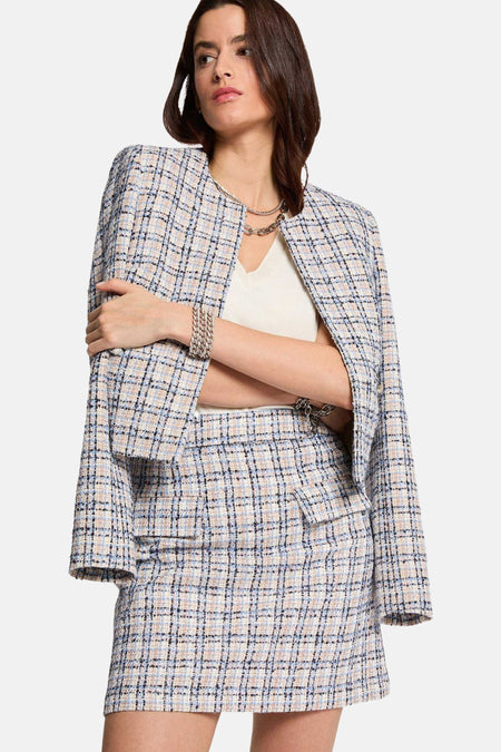 Mini-jupe multicolore de Morgan de Toi, à motif carreaux, avec un blazer assorti, portée avec un haut blanc et des bijoux argentés.
