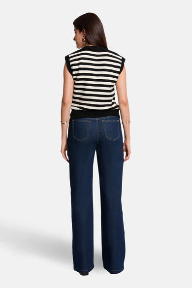 Gilet multicolore de Morgan de Toi, à rayures horizontales noires et blanches, porté avec un jean bleu.
