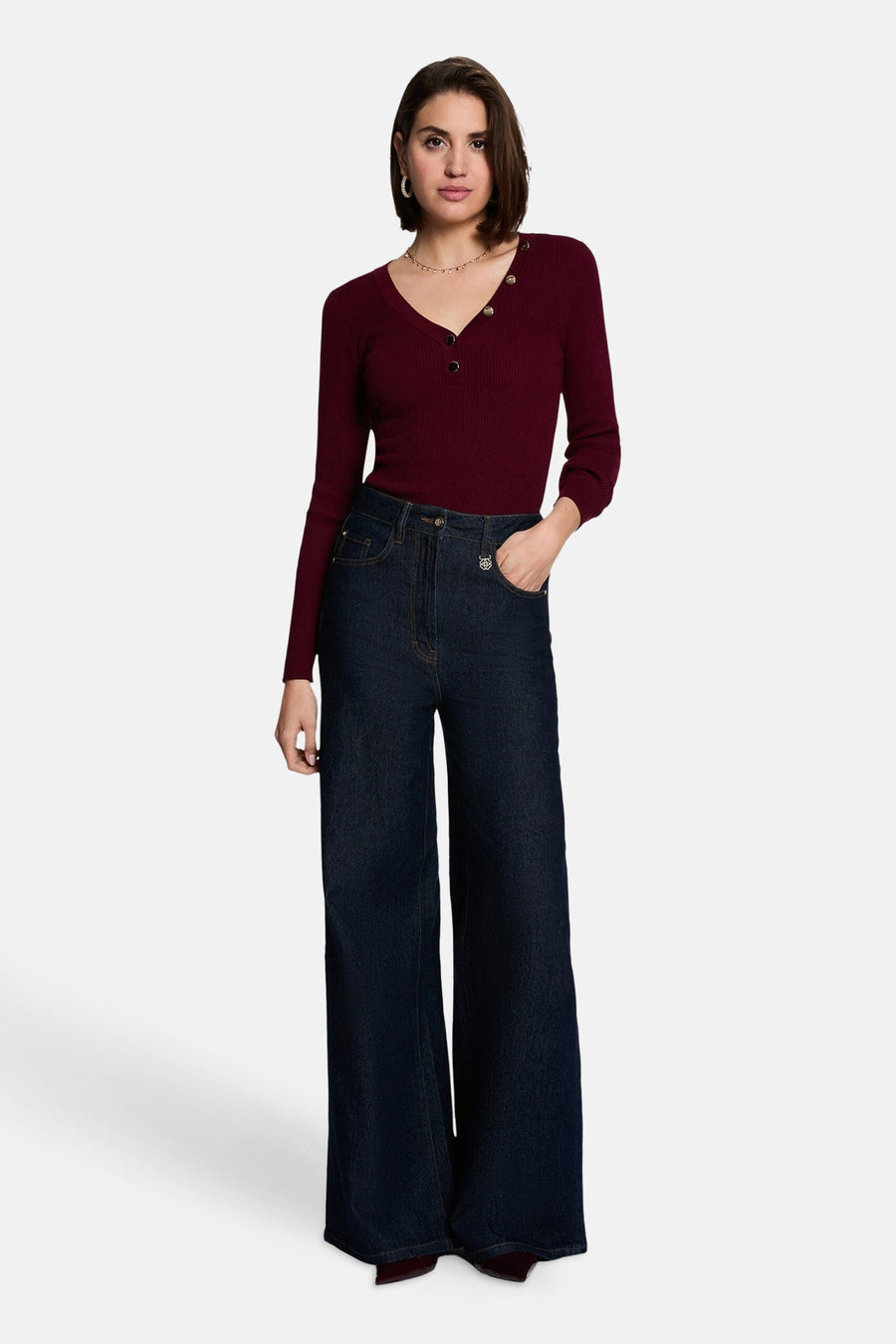 Burgundy ribbed V-neck long-sleeve sweater with front buttons, worn with dark wide-leg jeans and a delicate necklace, full-length front view.