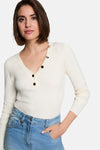 Ecru ribbed V-neck sweater with black and gold buttons, worn with blue jeans, front view