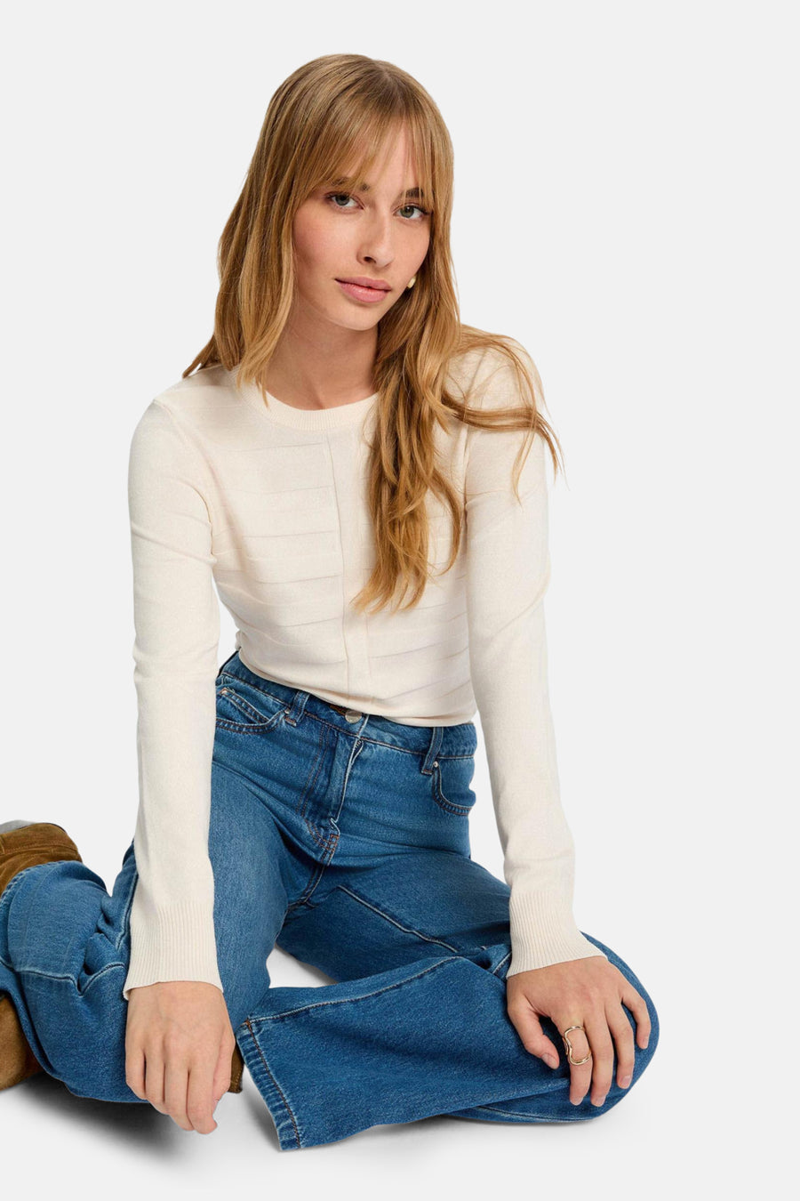 Ecru trui met ronde hals van Morgan de Toi, met gestructureerd patroon van horizontale strepen op een blauwe jeans.