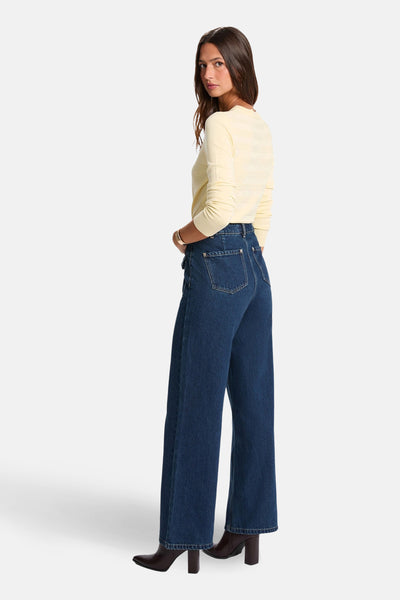 Pull à col rond jaune de Morgan de Toi porté avec un pantalon large en denim bleu et des bottines marron.
