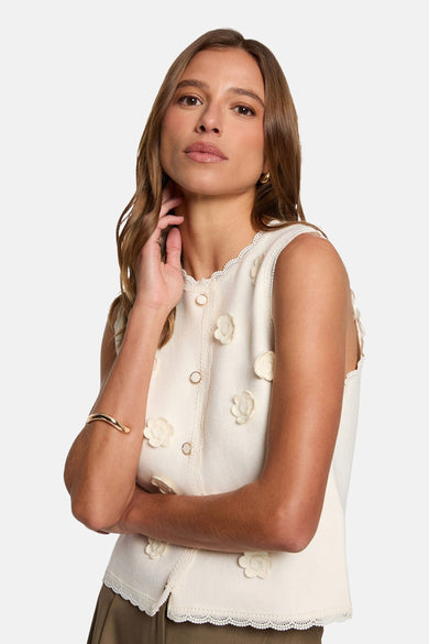 Ecru vest van Morgan de Toi, mouwloos, versierd met kant, gedragen met een bruine broek.