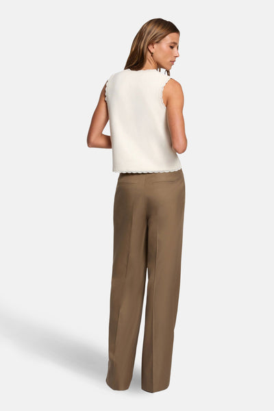 Cardigan écru de Morgan de Toi, sans manches, orné de dentelle, porté avec un pantalon marron.