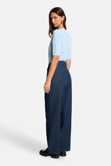 Pull à col rond bleu de Morgan de Toi, à manches courtes avec motif jacquard 'LOVE', vu de dos porté avec un jean ample foncé et des chaussures noires.