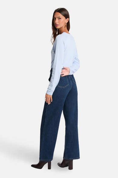 Pull bleu à col rond de Morgan de Toi, porté avec un pantalon foncé et des bottines marron à talon.