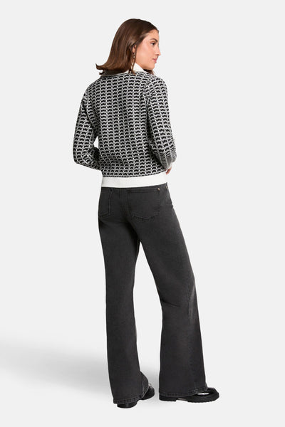 Cardigan noir de Morgan de Toi, avec motif à carreaux, porté avec un jean noir bootcut.
