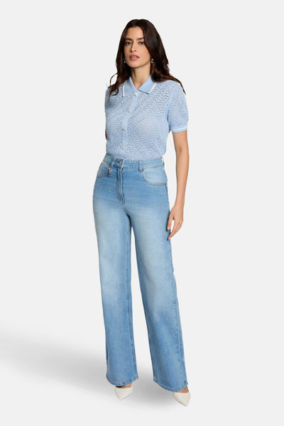Pull bleu de Morgan de Toi, à maille ajourée, porté avec un jean taille haute et des escarpins.
