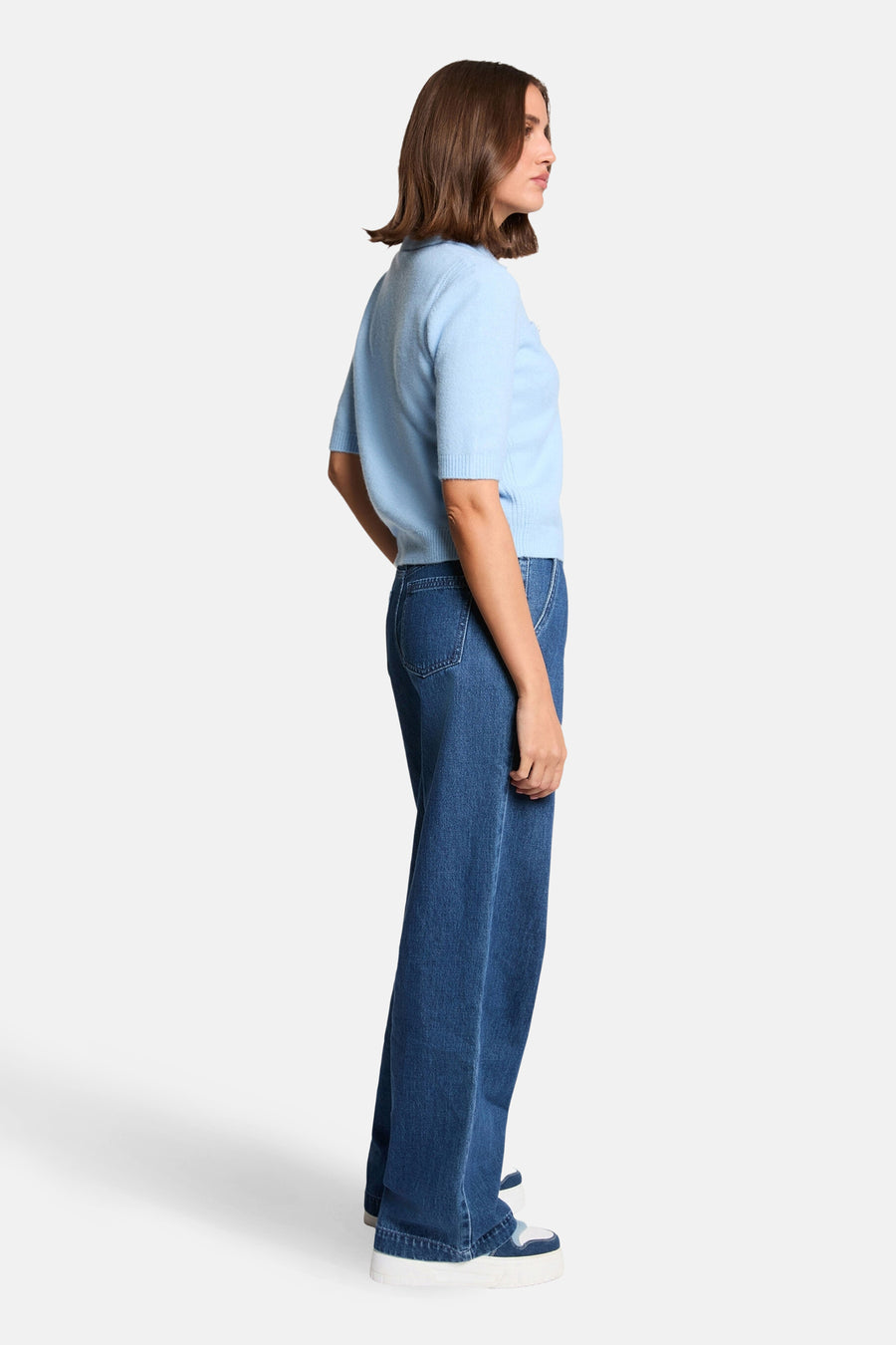 Pull bleu de Morgan de Toi, manches courtes, porté avec un jean ample et des baskets à plateforme, vue de côté.
