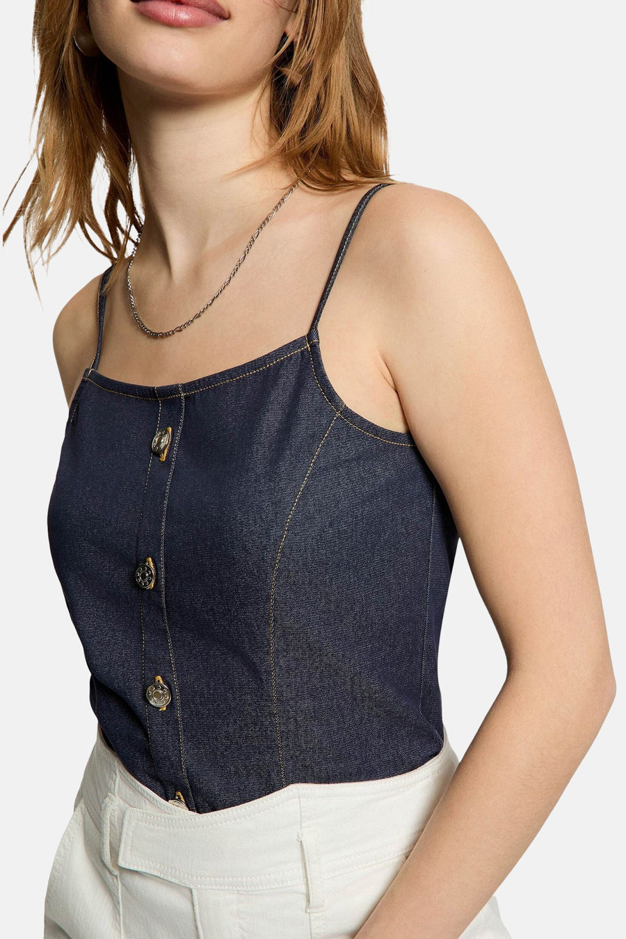 Top en jean bleu foncé de Morgan de Toi avec des boutons métalliques et des coutures contrastantes, porté avec un pantalon blanc.