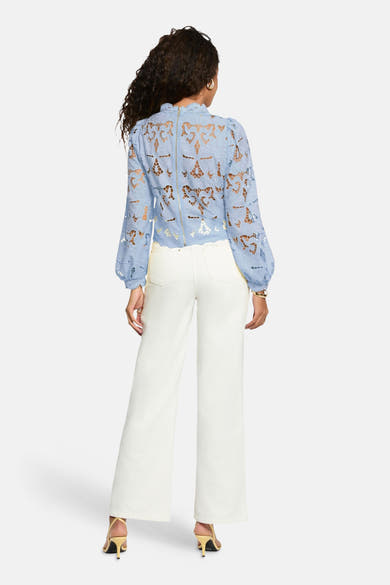 Blouse à manches longues bleue de Morgan de Toi, en dentelle florale ajourée, avec fermeture éclair au dos.