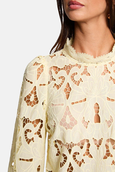 Blouse jaune en dentelle de Morgan de Toi, avec col montant et manches longues ajourées.
