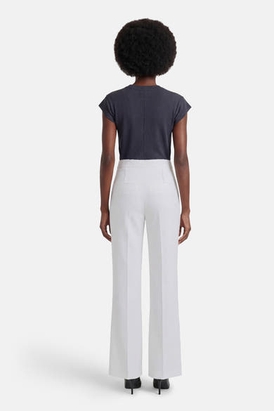 Witte pantalon van Morgan de Toi, wijde pasvorm met hoge taille, van achteren gezien met een donkergrijs topje en zwarte hakken.