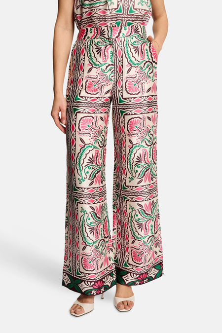 Pantalon multicolore de Morgan de Toi à motifs floraux et géométriques, coupe large, porté avec un haut assorti et des sandales.
