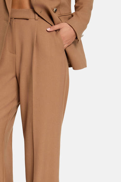 Pantalon de costume brun par Morgan de Toi, détail de la ceinture et plis structurés.
