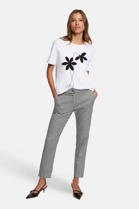 Pantalon à carreaux noir et blanc de Morgan de Toi, porté avec un t-shirt blanc à fleurs.