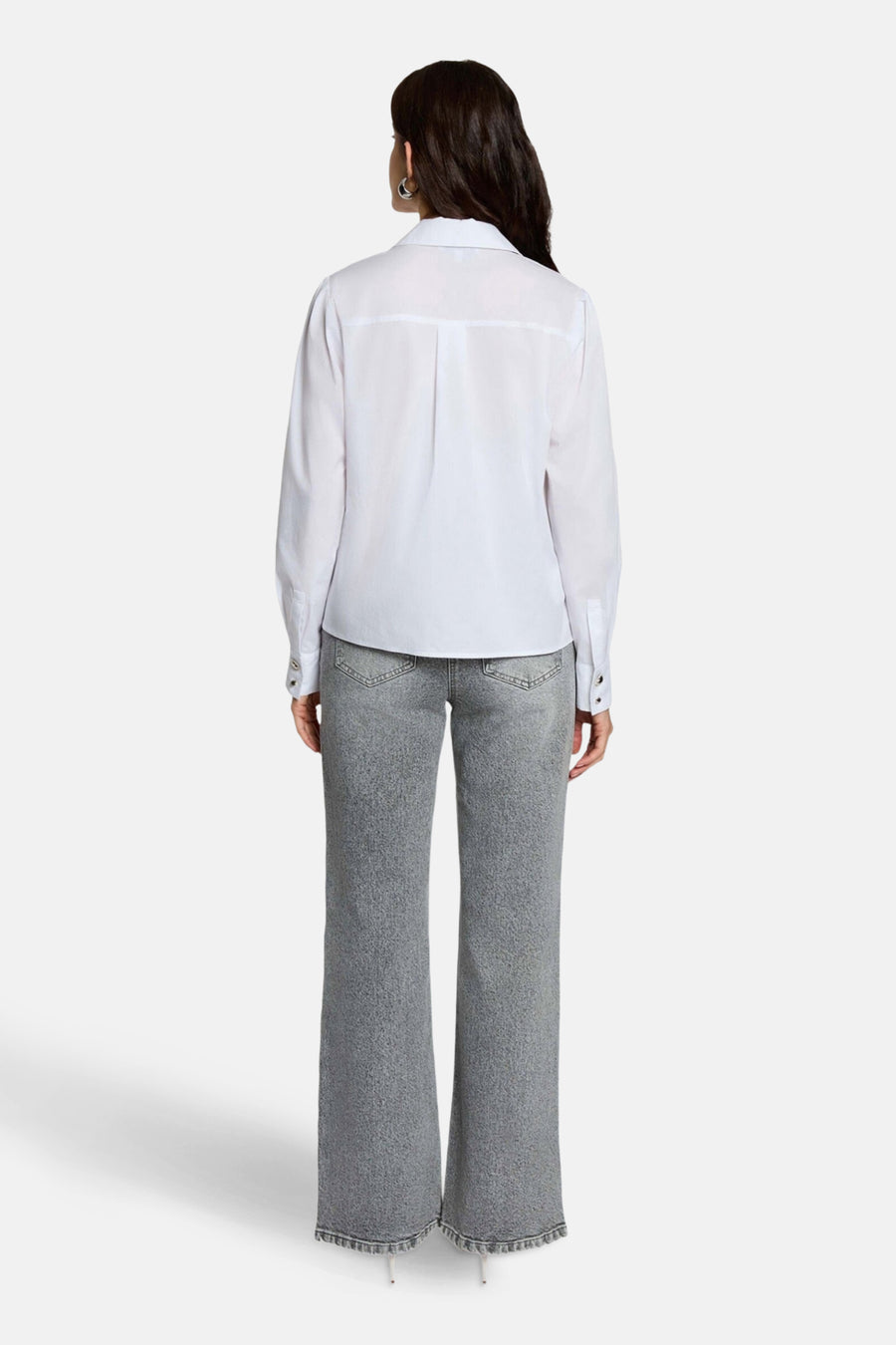 Jean large gris moyen de Morgan de Toi, coupe droite, porté avec une chemise blanche à manches longues.